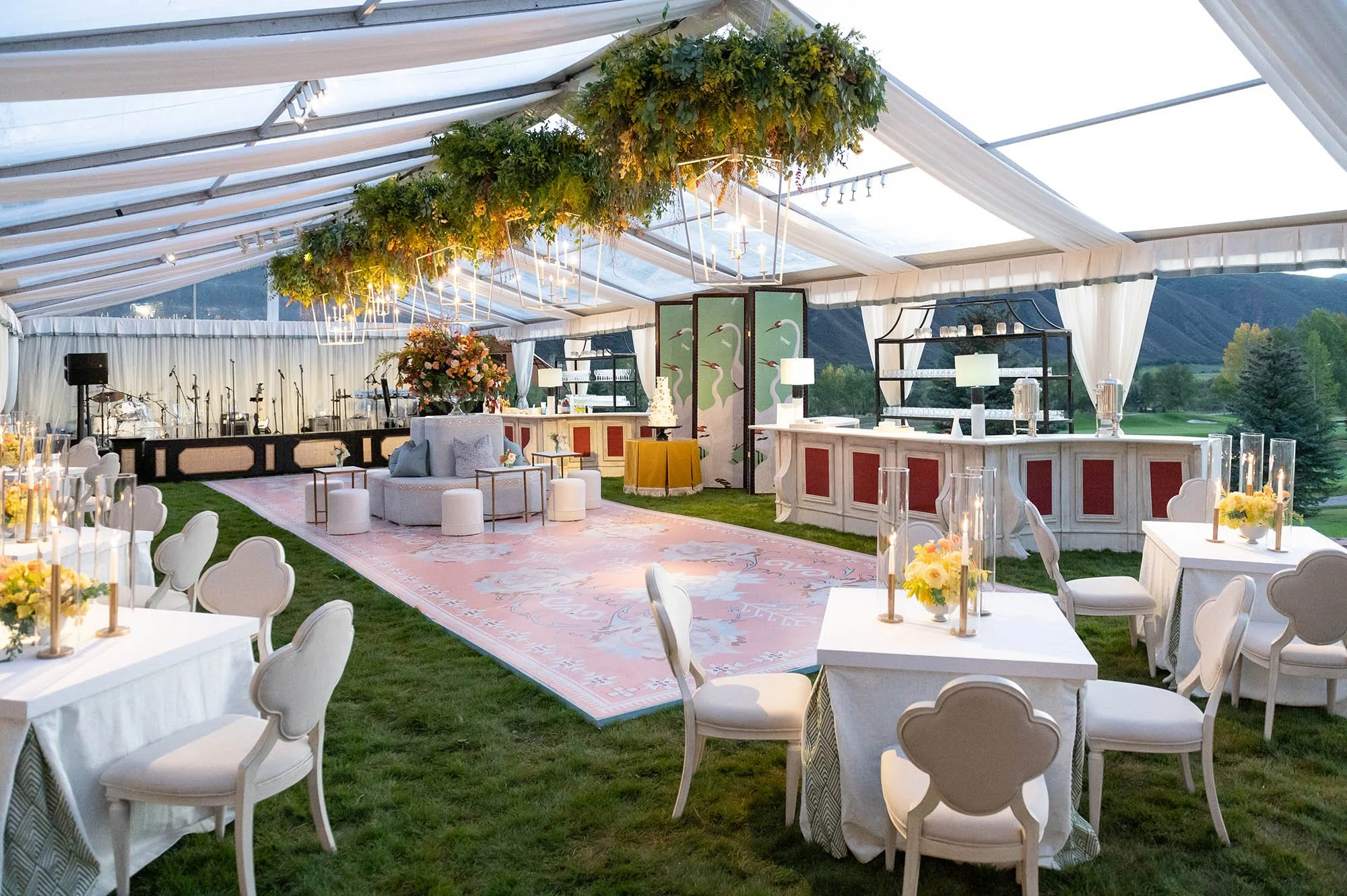 A tented lounge with white seating and overhead greenery